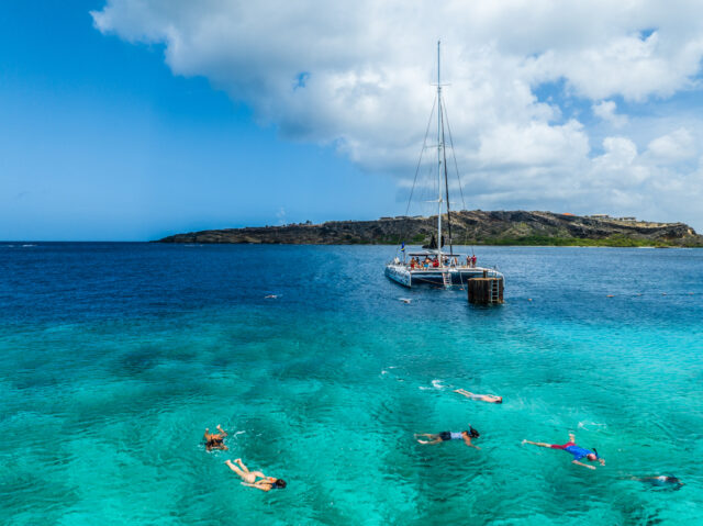 Catamaran in sea with people snorkeling